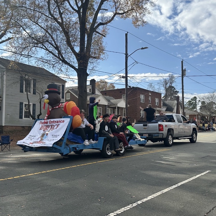 students riding on a blue trailer with an inflatable turkey 