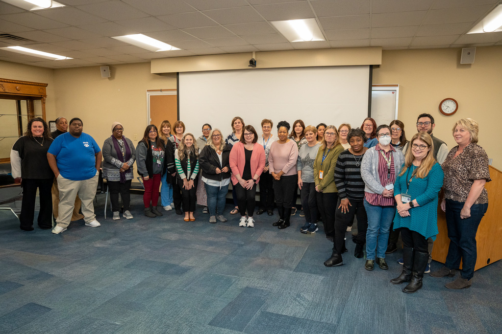 Large group photo of school treasurers lined up in front of a large projector screen