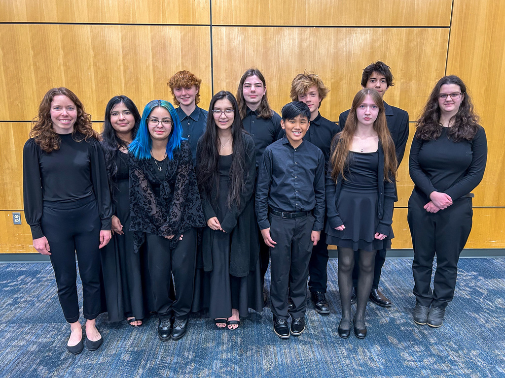A group photo of ten young people, likely the student ensemble, standing together and facing the camera. They are all dressed in black attire.