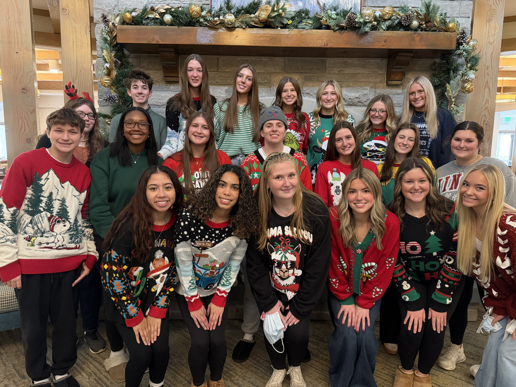 Group of students from Southern High School Leadership Class in festive Christmas attire in front of a large fireplace