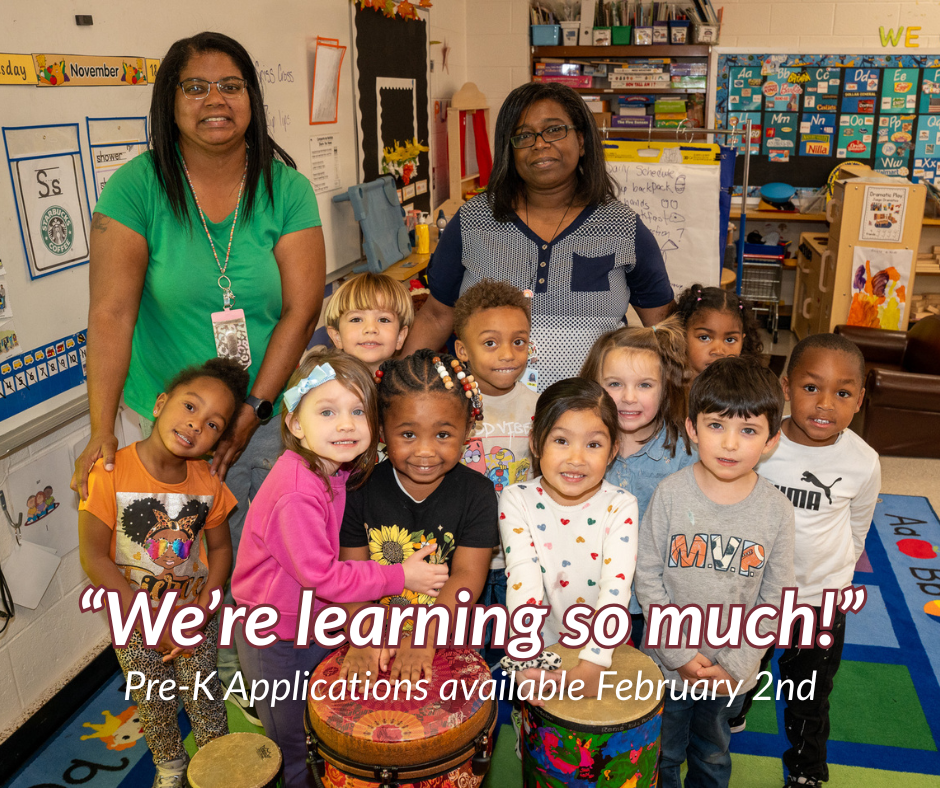 A Pre-K class of about 10 students and two teachers standing behind them