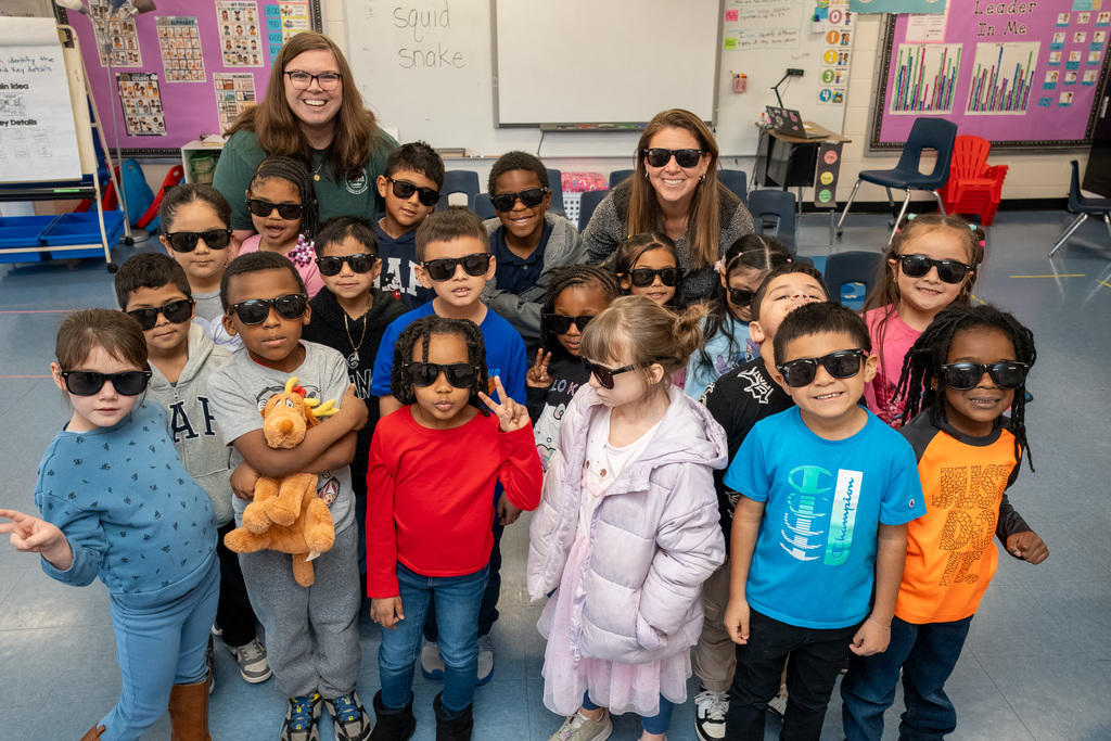 A kindergarten class, most wearing black sunglasses, posed for a class photo