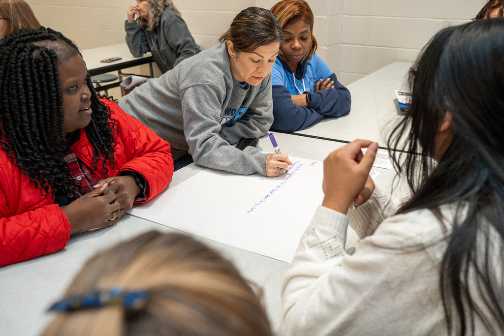 Office staff from schools concentrate on a group exercise around poster paper