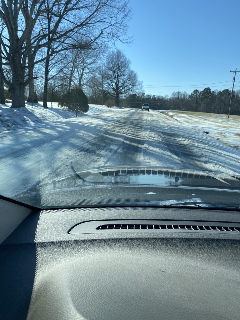 An icy road from the perspective of inside the car looking out the windshield