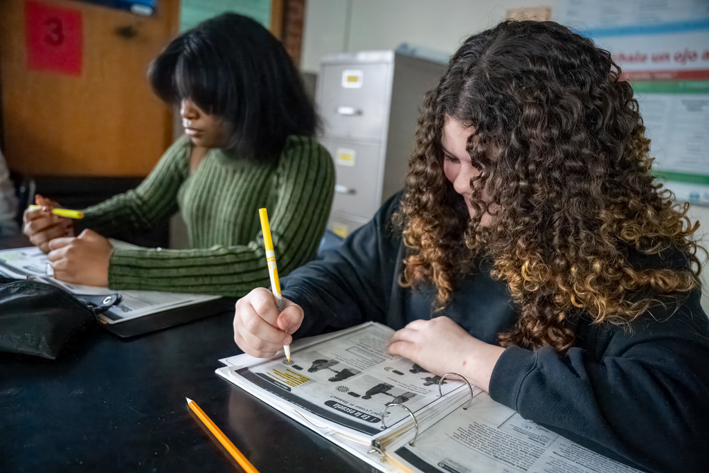 Two students highlight terms in their binders during a Spanish class
