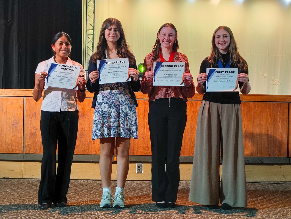 Four participants in the Region 5 science fair on stage being recognized