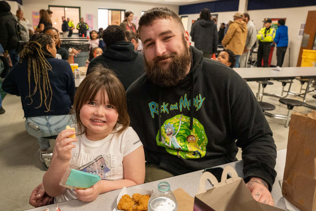 A parent poses with their child at lunch