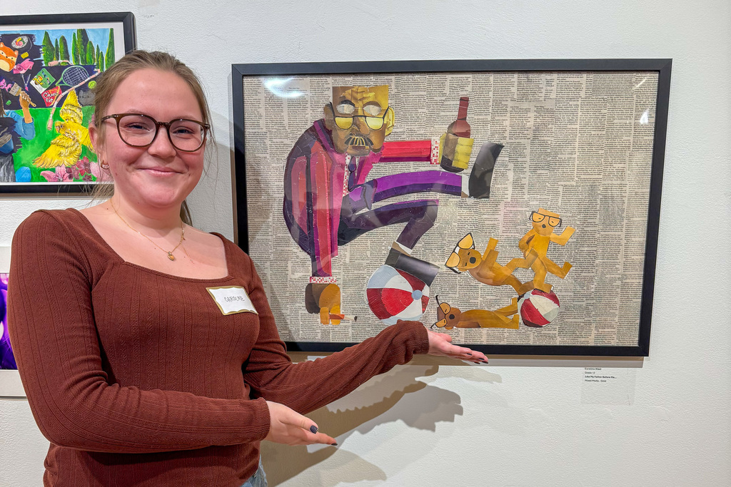 Carolina West standing beside one of her exhibited art pieces