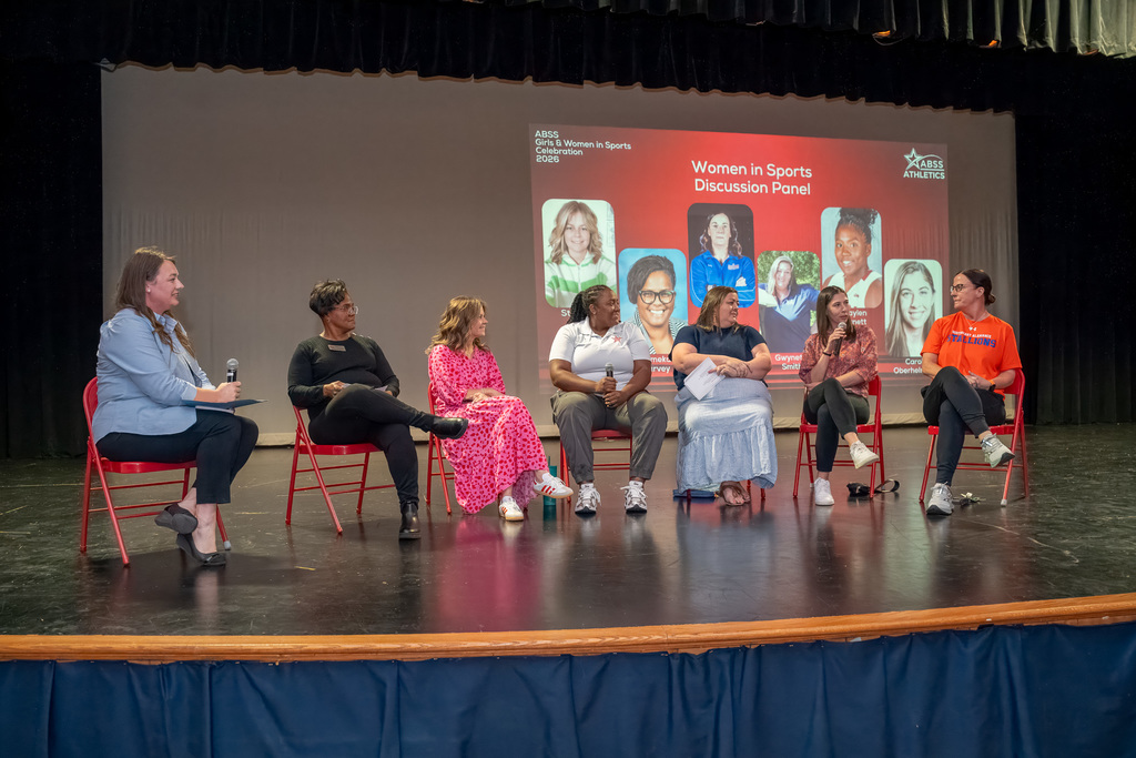A wide group shot of numerous female student-athletes and staff standing together on the Southern Alamance High School auditorium stage under bright spotlights during the 2026 celebration.