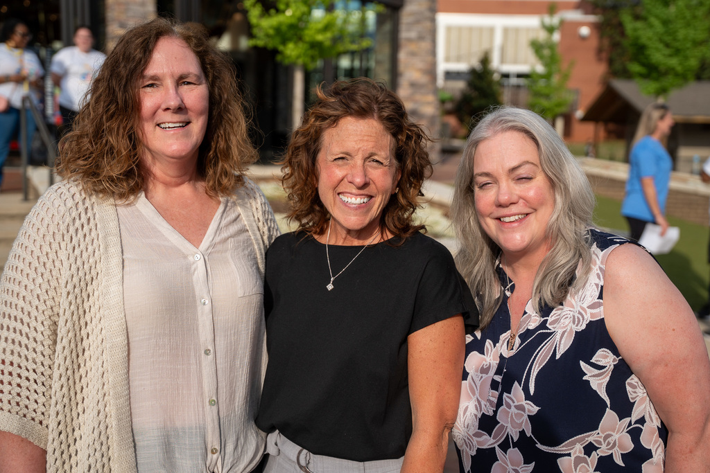 A professional group photo of three women smiling outdoors at the park during the Week of the Young Child celebration.