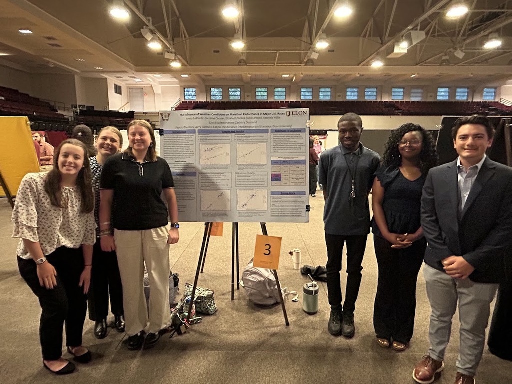 A group of six Williams High students standing beside their research project