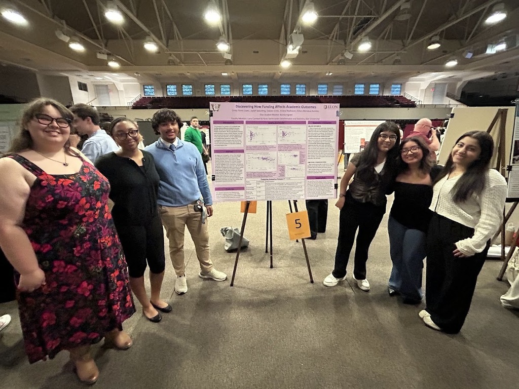 A group of six Williams High students standing beside their research project