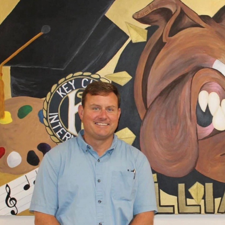 Mr Bryan in front of a painting with a bulldog 