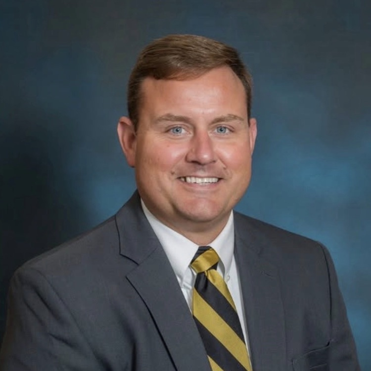 Mr Bryan in a tie with a blue background
