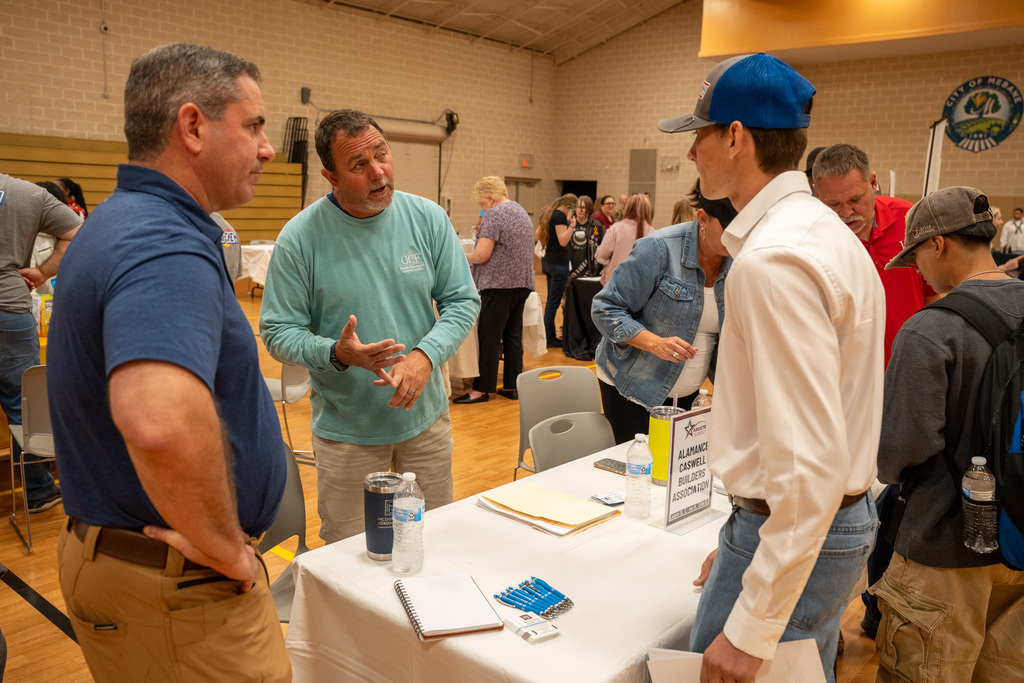 A high school student talks to men at the Alamance Caswell Builders Association table