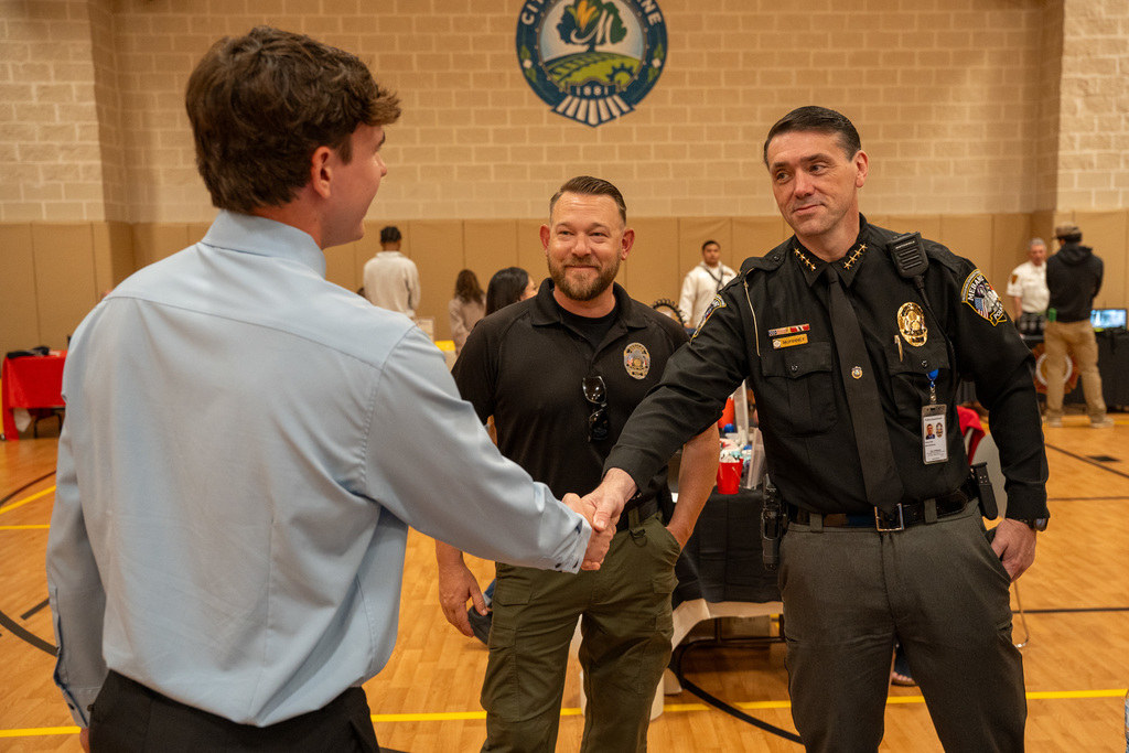 A high school student shakes the hand of a police office
