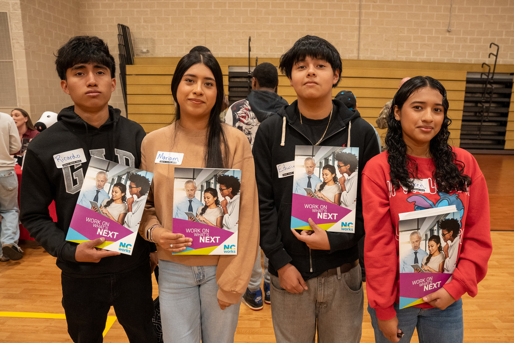 Four teenages holding NC Works packets during the Job Fair