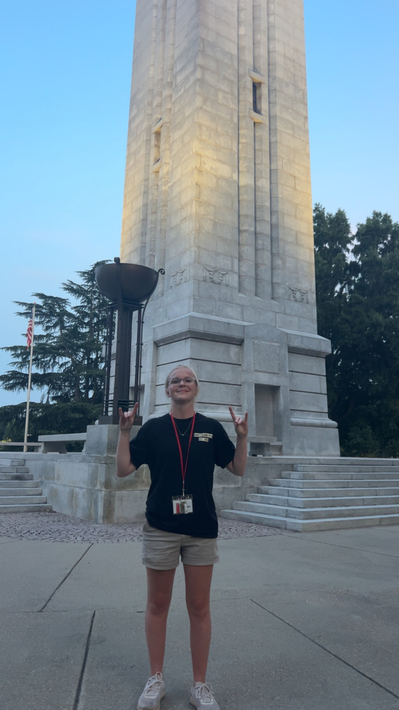 Alivia giving the wolfpack hand signs in front of the NC State bell tower