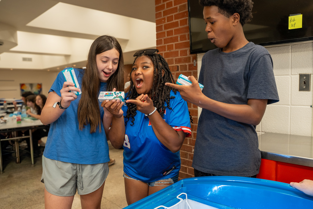 Three students act surprised and amazed at the free ice cream they just received
