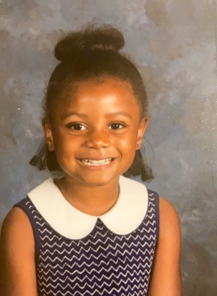 A young Chloe wearing a striped dress with white collar
