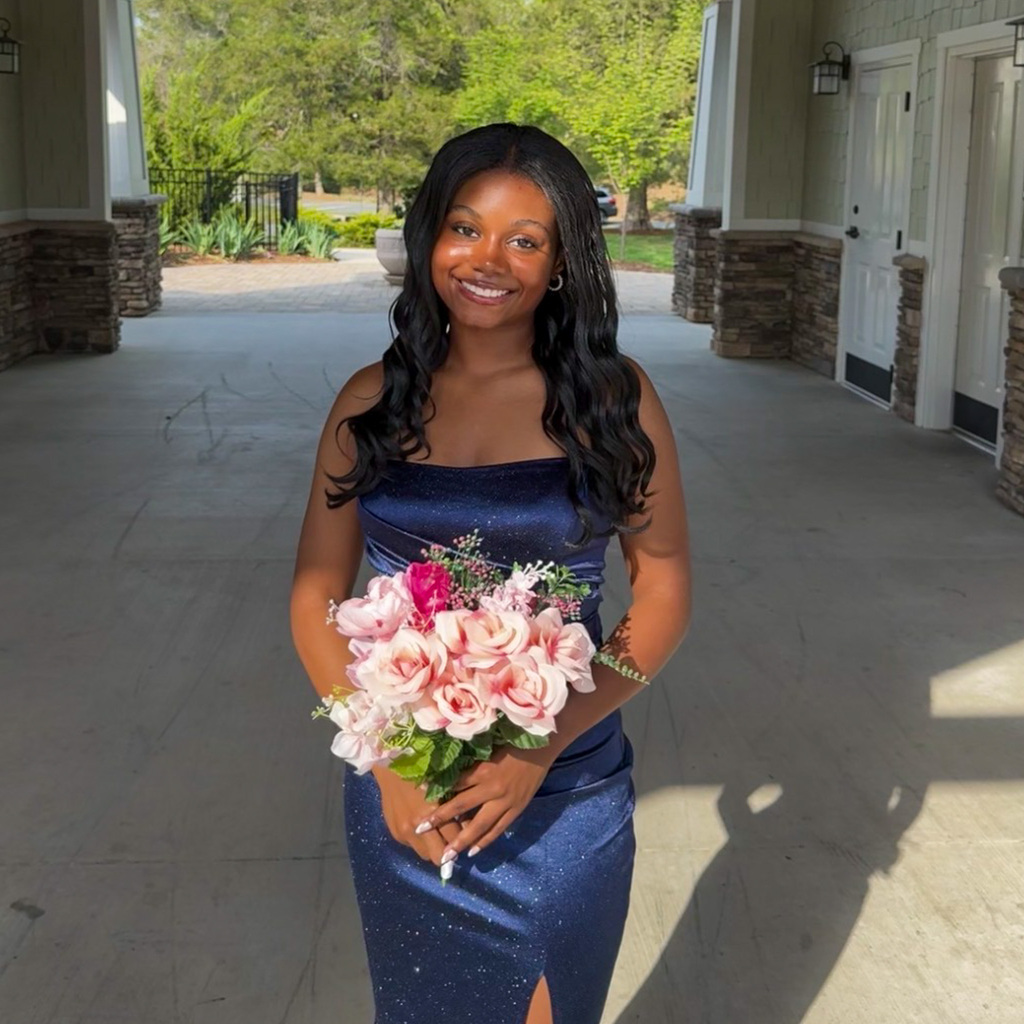 Chloe in formal blue dress and holding a floral arrangement