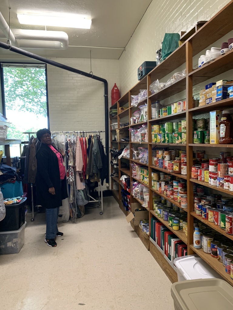 LaSonya standing in her office next to a large wall with wooden shelves stocked full of food pantry items