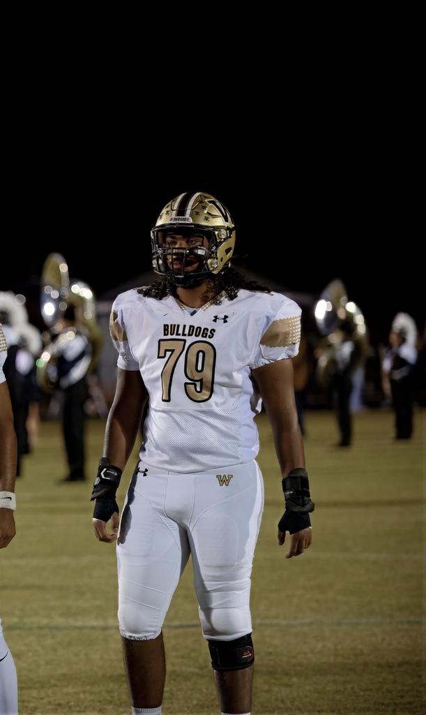 Kinston in white Bulldogs football gear standing on the football field