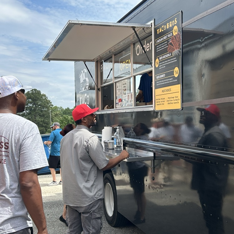 Varioud staff line up in front of a food truck 