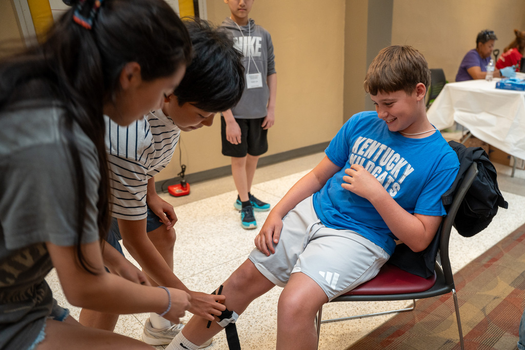 Two students practice tying a splint on a student as part of a career demonstration