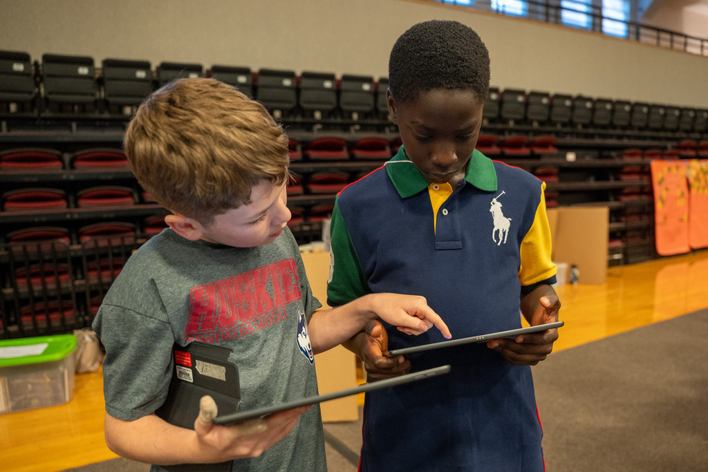 Two students look at iPads together as they document the activities of the day