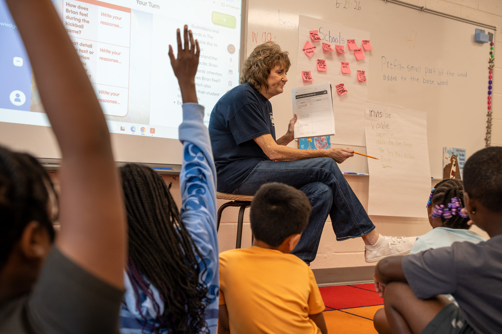 A teacher prompts a small group during a reading lesson