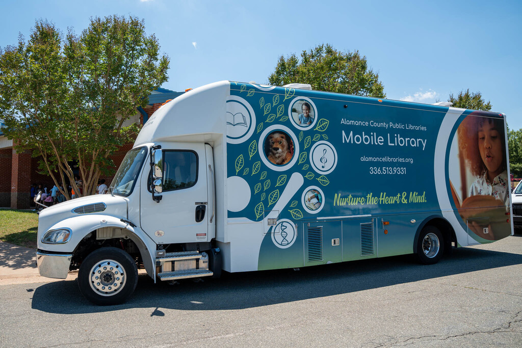 A large mobile library truck parked outside of an elementary school