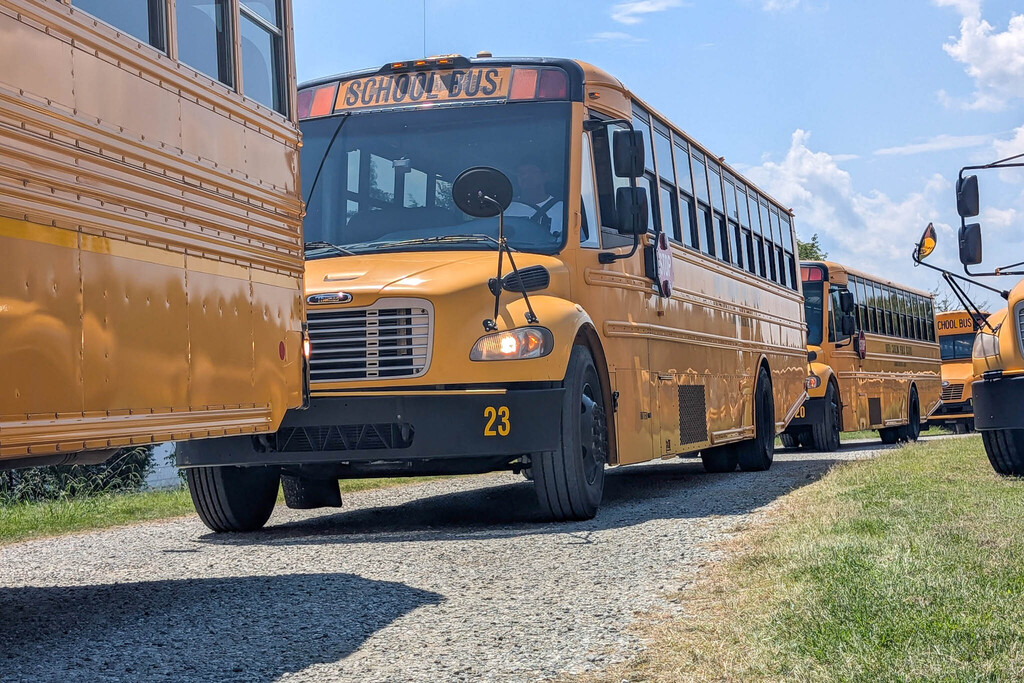 A line of yellow school buses on a gravel road, low camera angle