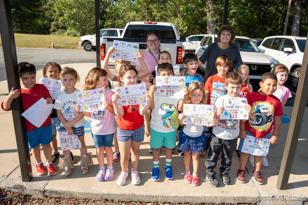 An elementary class holds signs thanking first responders while they wait for a Heroes Day parade to begin.