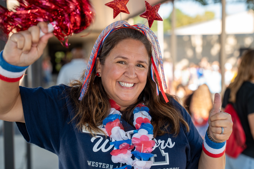 A staff member wearing red, white, and blue smiles enthuasiastically.