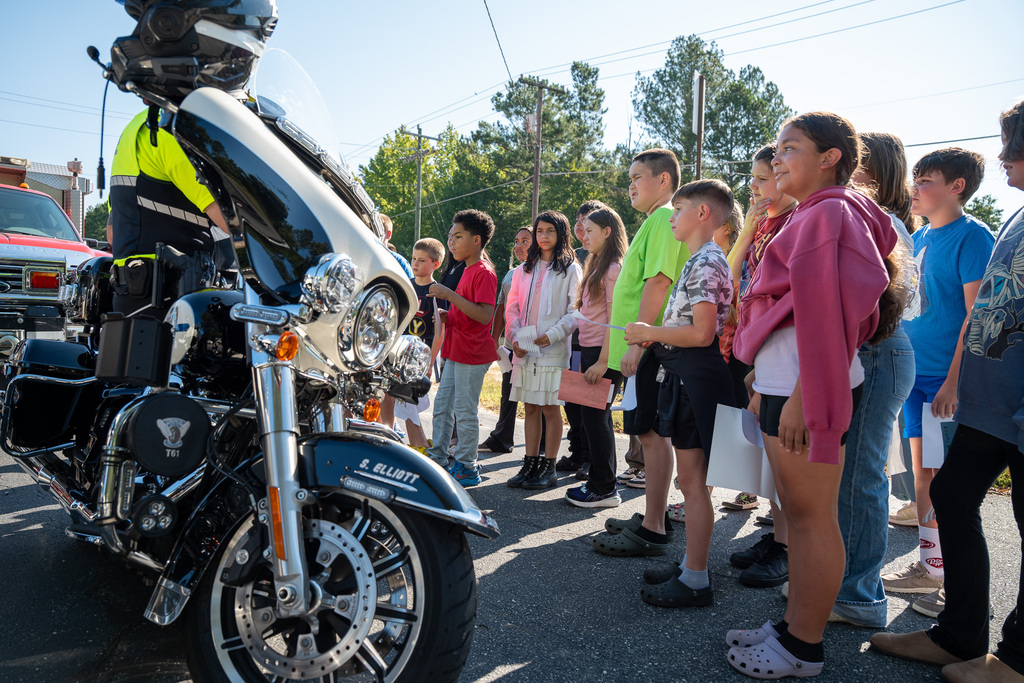 Students look on as a Burlington Police Department officer explains his duties.  In the foreground is the front of his motorcycle.