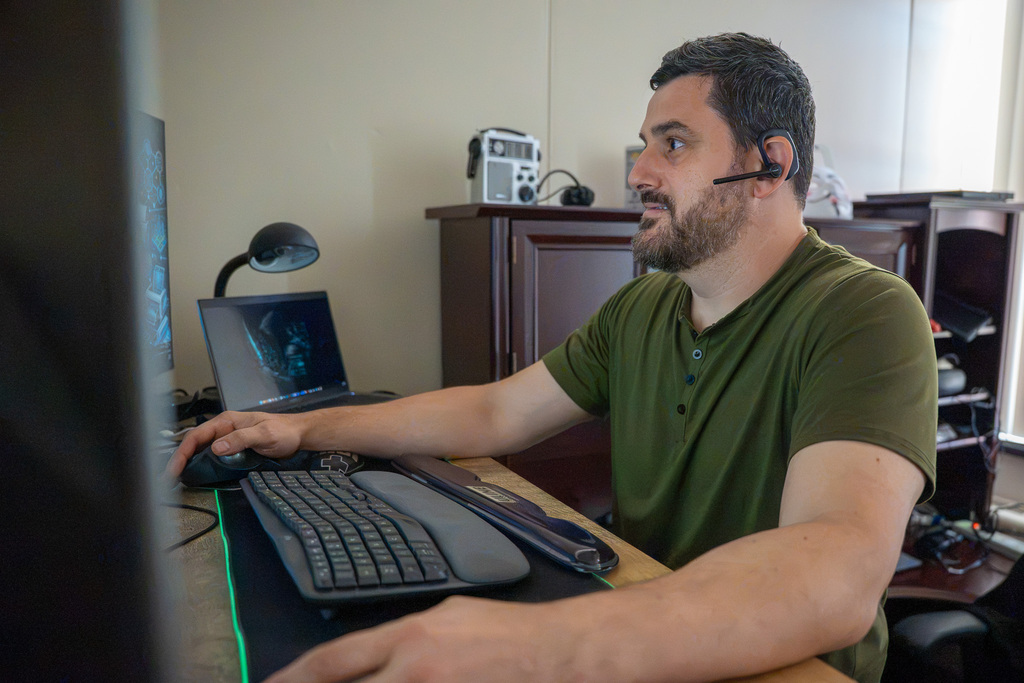 A technician in a green shirt looks towards his computer screens while responding to a support ticket