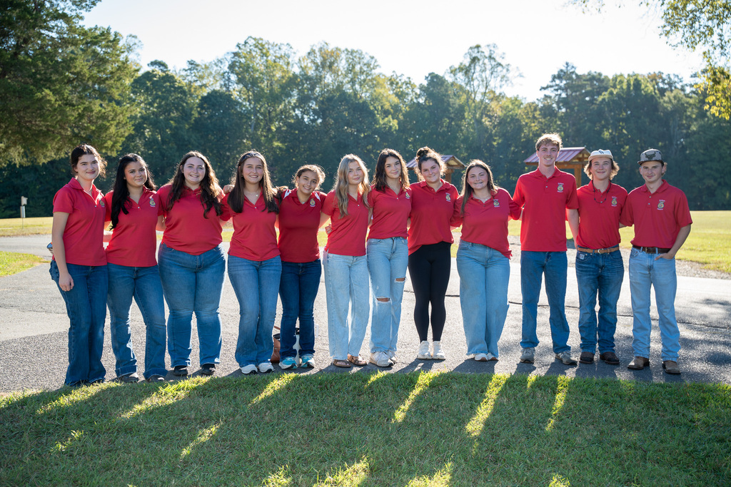 A line of high school students wearing matching red polos and jeans outdoors