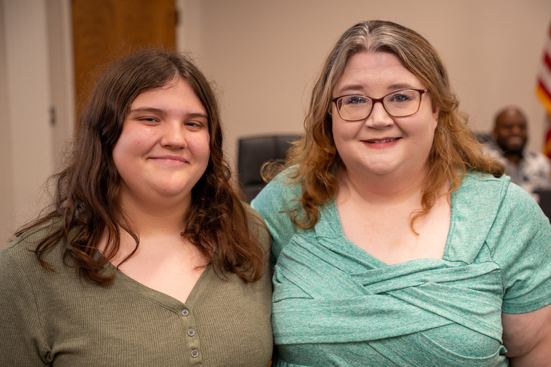 Ashley wearing a green shirt next to a younger woman in a darker green shirt