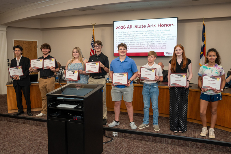 Eight students holding certificates in front of the board of education meeting during recognition
