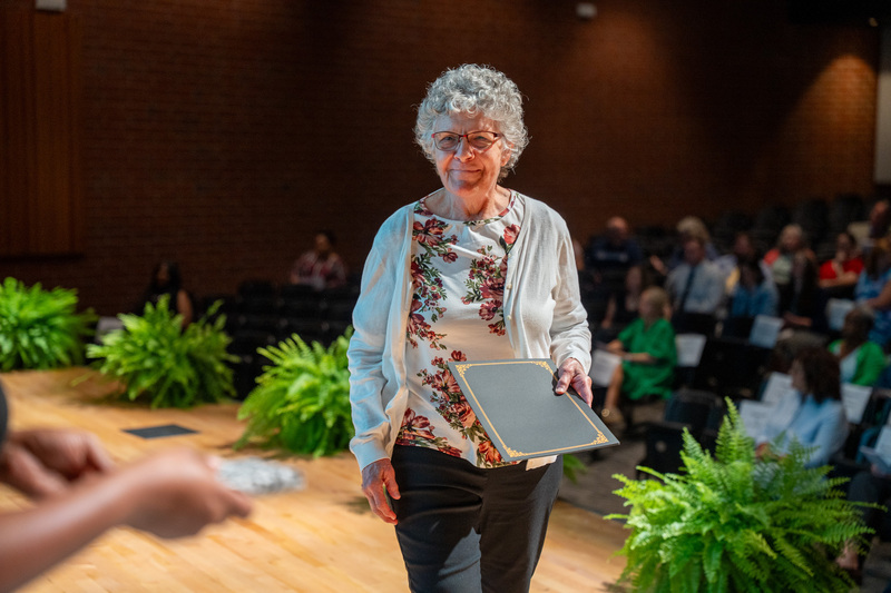 A retiree walks towards a Human Resources staff member to accept a certificate