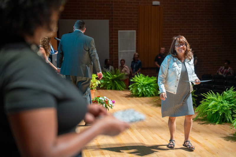 A retiree walks towards a Human Resources staff member to accept a certificate
