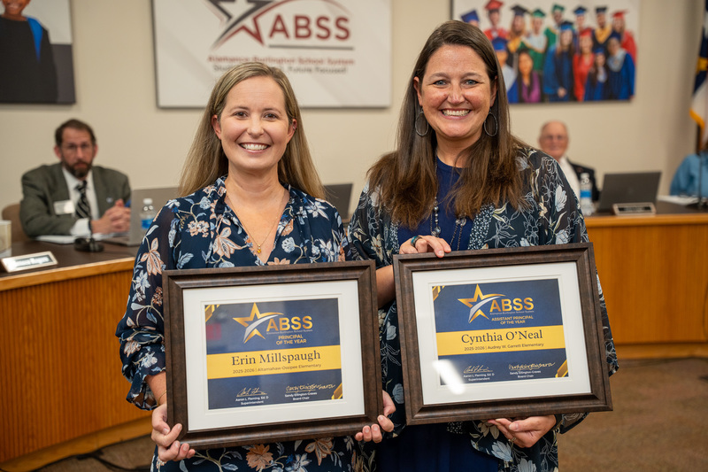 Photo of Erin Millspaugh and Cynthia O'Neal wearing blue floral outfits, holding a blue and gold award certificates.