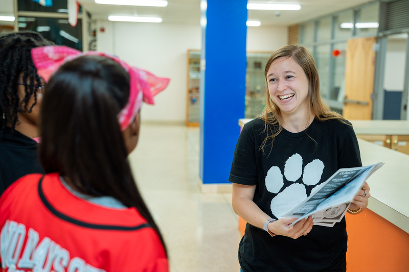 Annie Goldberg laughing while talking to students in the hallway at Broadview