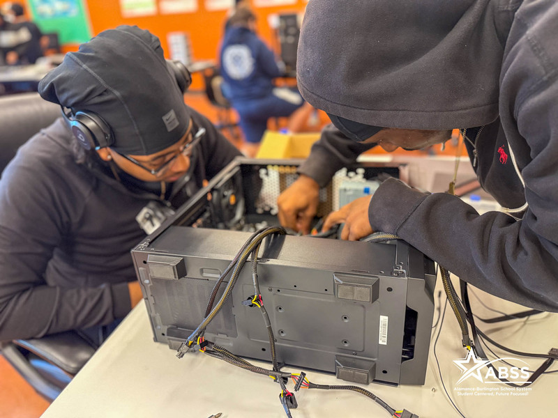 Two students assembling a computer on a worktable