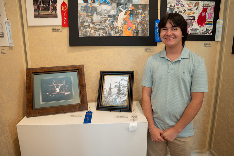 Brandon Kennedy standing besides his photographs on display at Alamance Art Museum