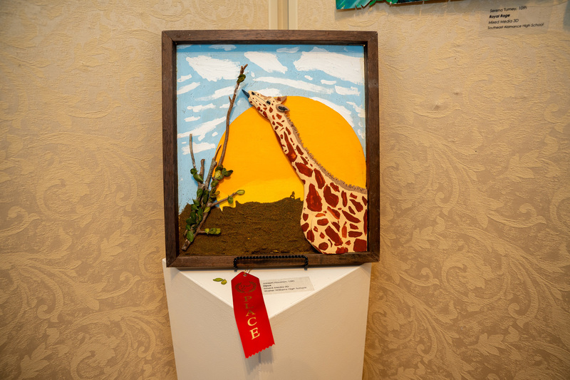 Artwork from Joseph Houston depicting a giraffe eating a branch with a large sun behind it