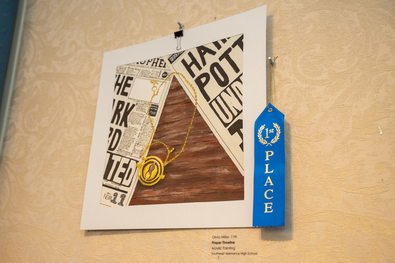 An acrylic painting showing a locket on top of papers on a desk, detailed, by student Olivia Miller