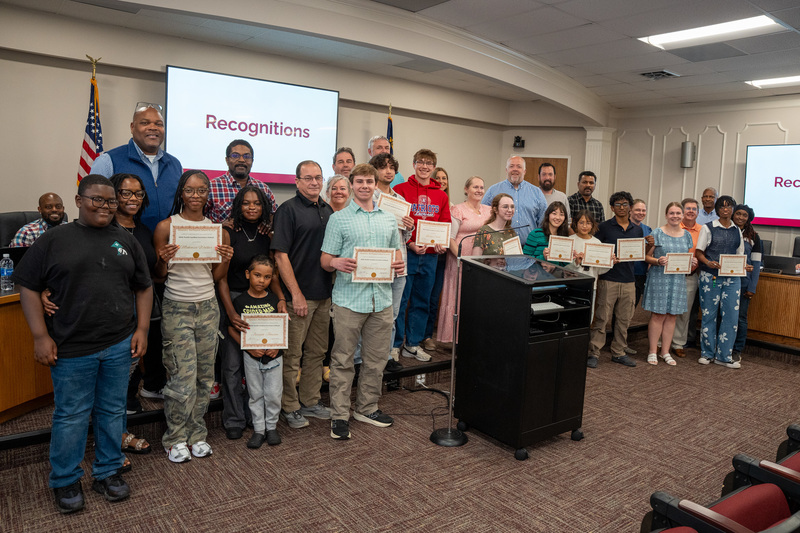 A large group in the Board room featuring Governor's school students, families members, and Board members.