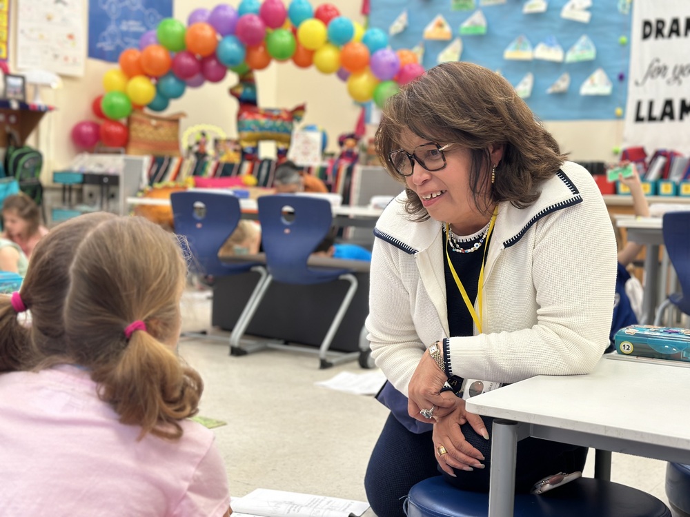 Teacher leans down to talk to student